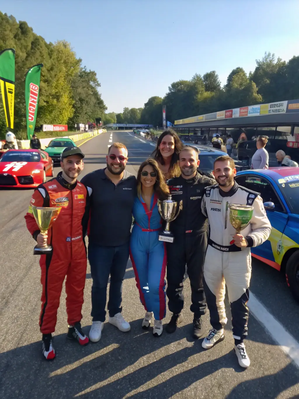 A diverse group of Club Pro Team Sport De Grenoble members celebrating a successful race day, emphasizing the club's inclusive and supportive community.